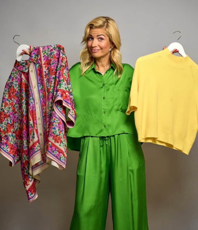 Susan Sideropoulos hält ein buntes Blumenmuster-Shirt und einen gelben Pullover vor sich.