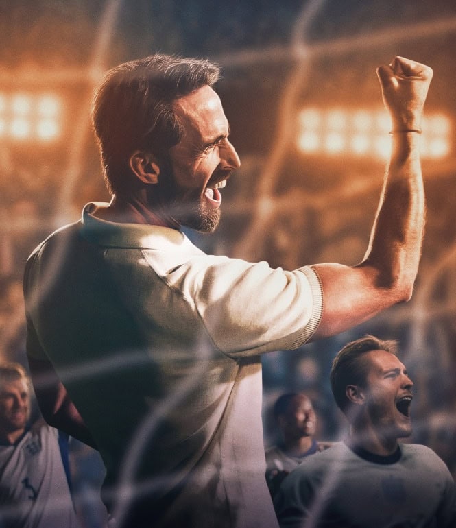 Fußballtrainer jubelt mit geballter Faust vor einem Stadionpublikum.