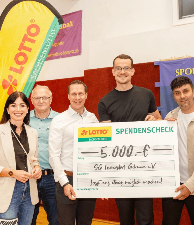 Fünf Personen stehen nebeneinander und präsentieren einen symbolischen Spendenscheck von Sachsenlotto über 5.000 Euro für die SG Lückersdorf-Gelenau e. V.; im Hintergrund sind ein Lotto-Banner und ein Vereinsbanner zu sehen.