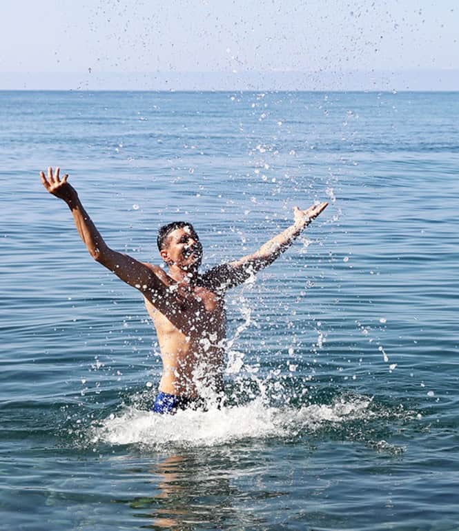 Mann springt freudig ins blaue Meerwasser