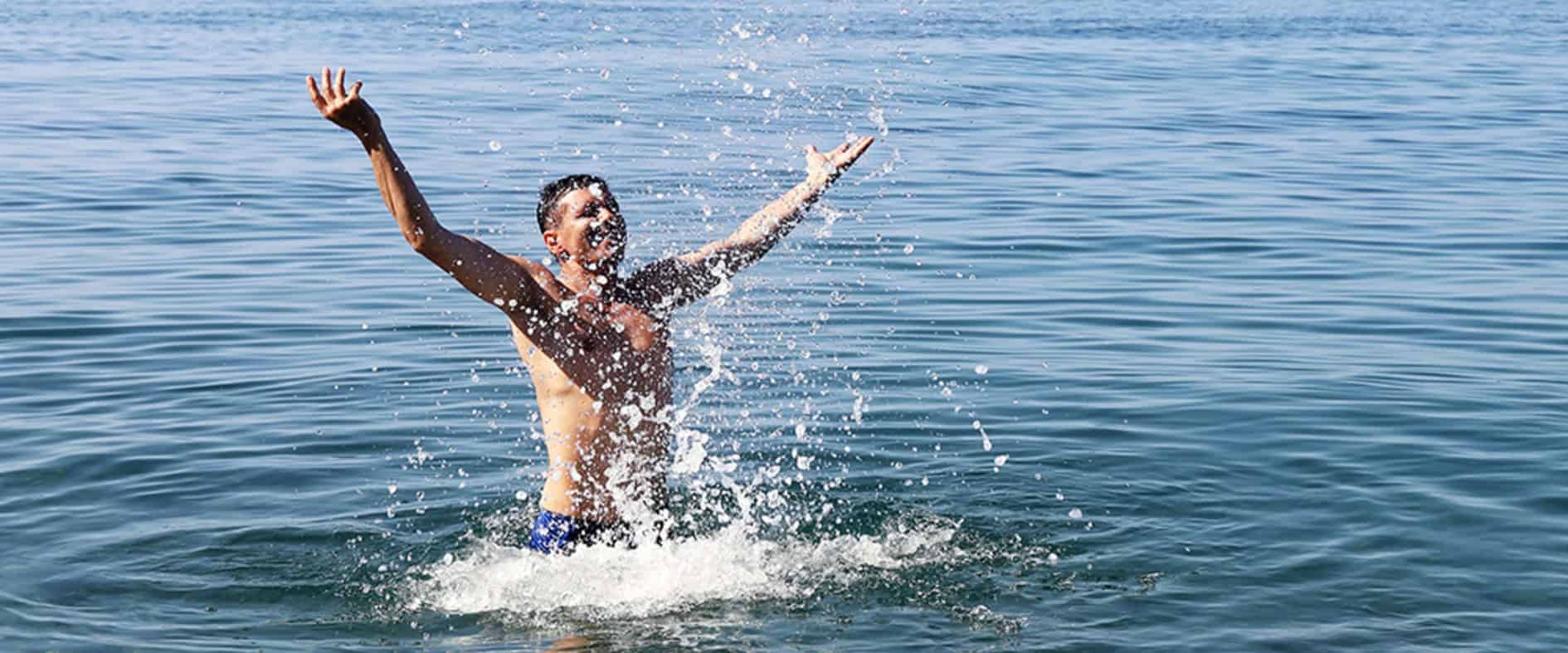 Mann springt freudig ins blaue Meerwasser