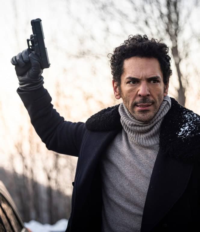 Schauspieler Tomer Sisley als Largo Winch mit gezückter Waffe in einer spannungsgeladenen Szene.