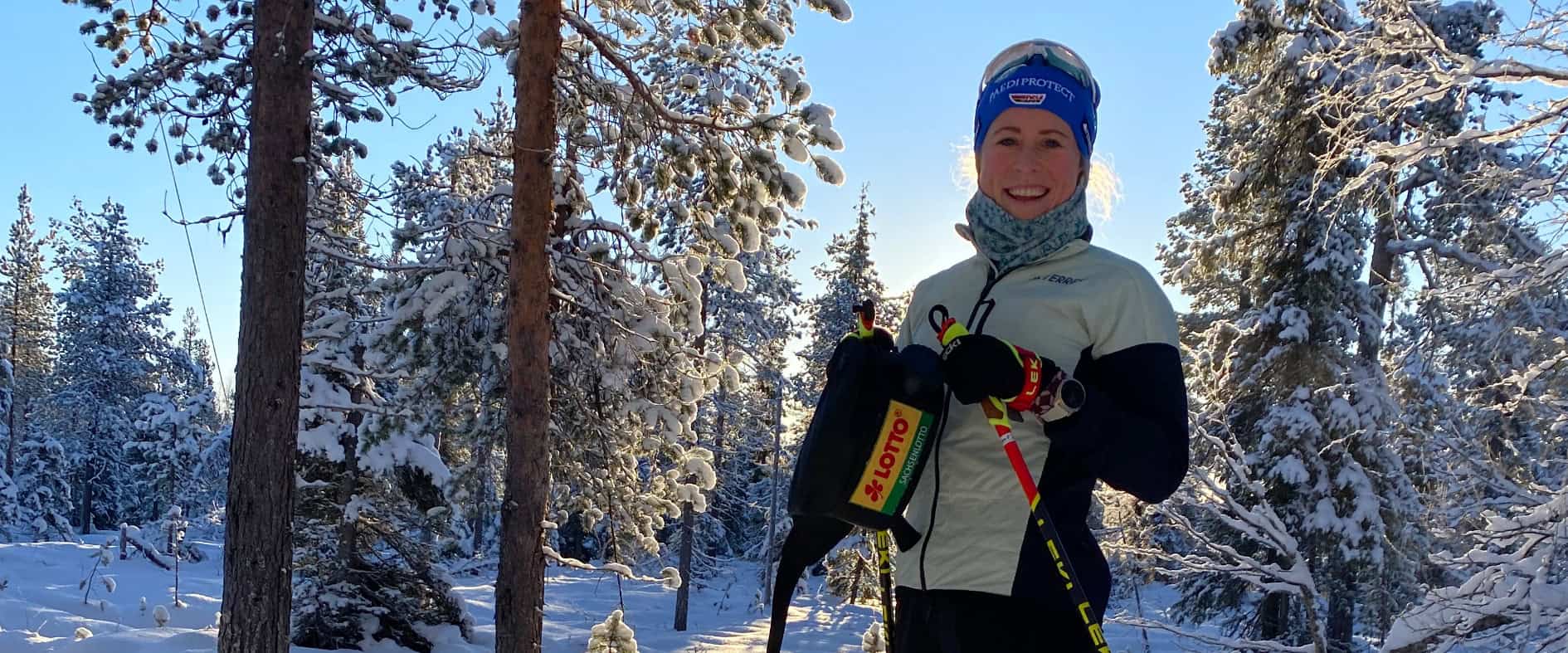 Sachsenlotto-Möglichmacherin Katharina Hennig steht im Schnee und hält Langlaufski sowie Stöcke in den Händen