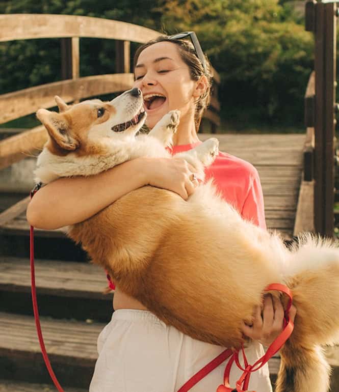 Eine Frau umarmt glücklich ihren großen, flauschigen Hund im Freien