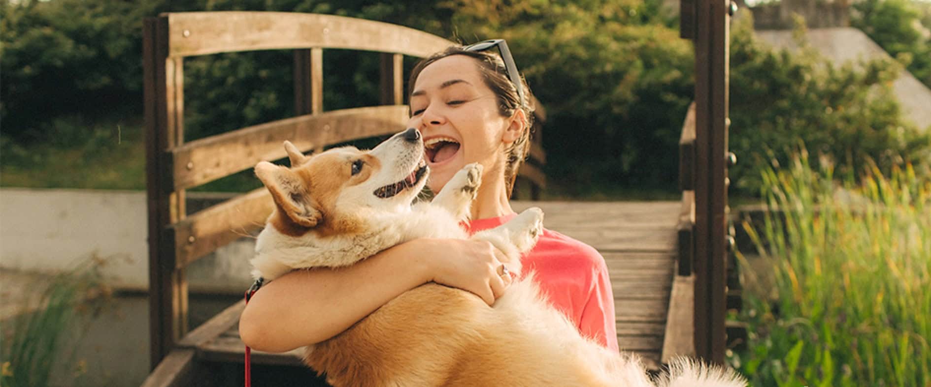 Eine Frau umarmt glücklich ihren großen, flauschigen Hund im Freien