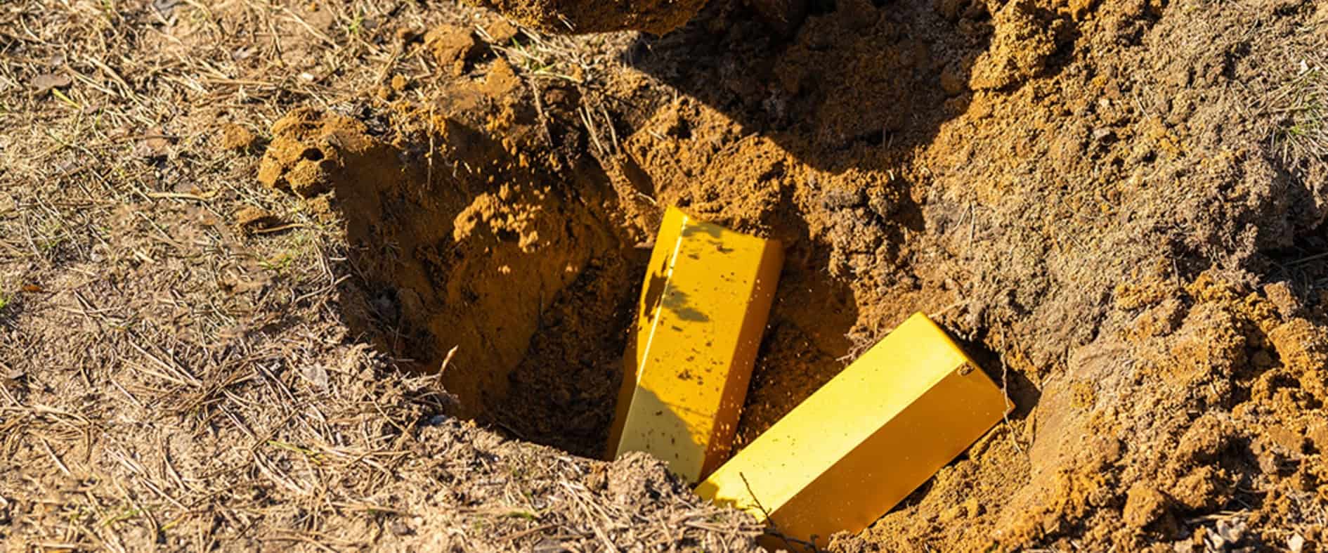 Spaten und Goldbarren in ausgehobener Erde