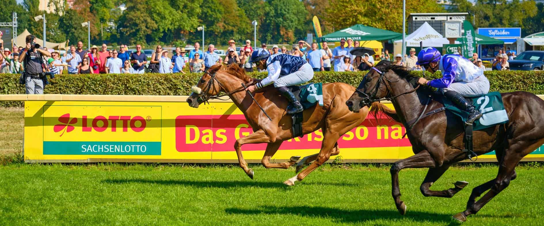 Partyrenntag: Galopprennen im Scheibenholz Leipzig mit zwei Jockeys auf der Zielgeraden vor Publikum