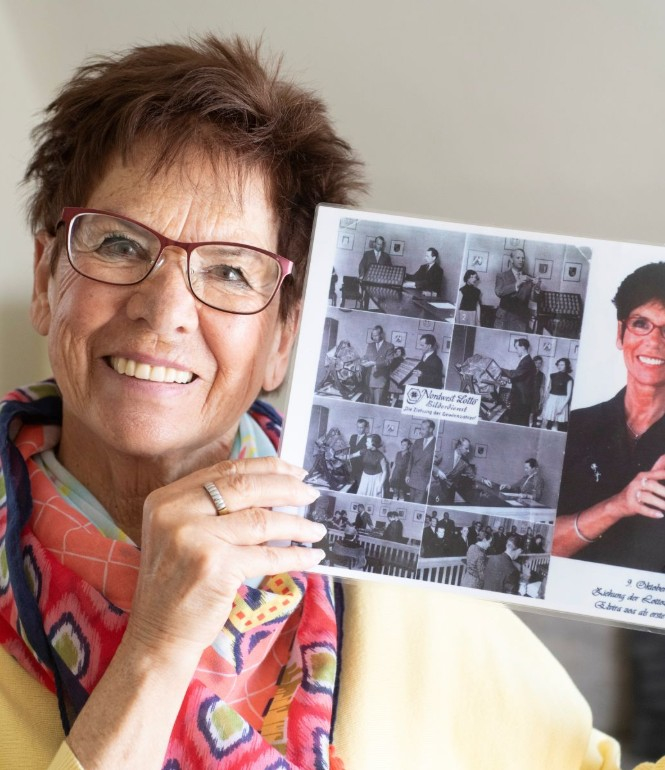 Elvira Hahn hält ein historisches Foto der ersten Lottoziehung 1955 in den Händen – sie war als Waisenkind die erste Lottofee.
