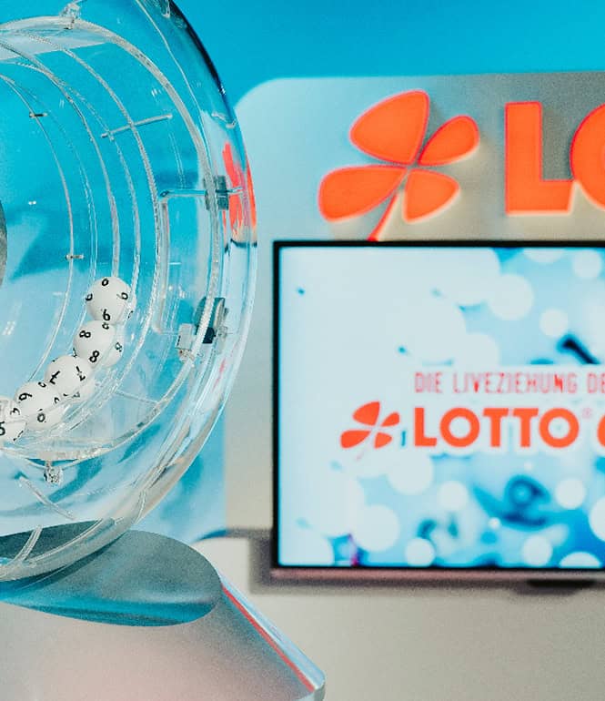Ziehungsstudio von LOTTO 6aus49. Im Vordergrund zu sehen ist die Trommel mit LOTTO-Kugeln, im Hintergrund ein Bioldschirm mit LOTTO-Logo