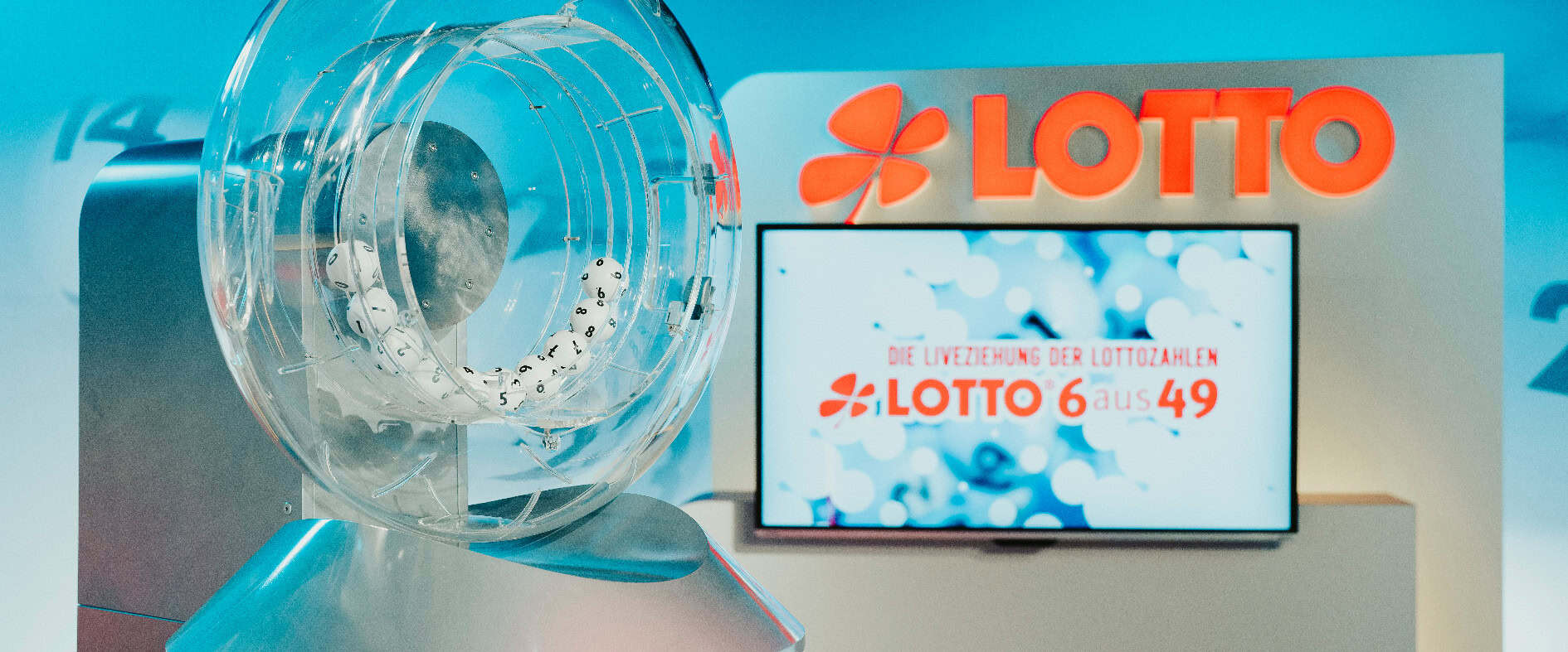 Ziehungsstudio von LOTTO 6aus49. Im Vordergrund zu sehen ist die Trommel mit LOTTO-Kugeln, im Hintergrund ein Bioldschirm mit LOTTO-Logo