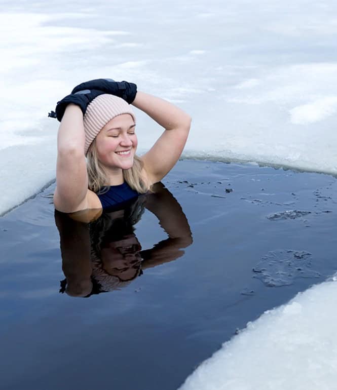 Frau im Neoprenanzug und Mütze im eiskalten Wasser