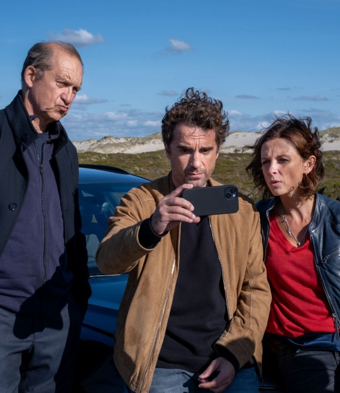 Peter Heinrich Brix, Oliver Wnuk und Julia Brendler als Nord Nord Mord-Ermittlerteam vor blauem Auto in Sylter Dünenlandschaft