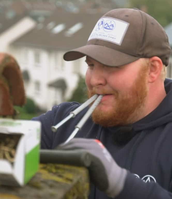 Handwerker in Arbeitskleidung arbeitet auf einem Dach