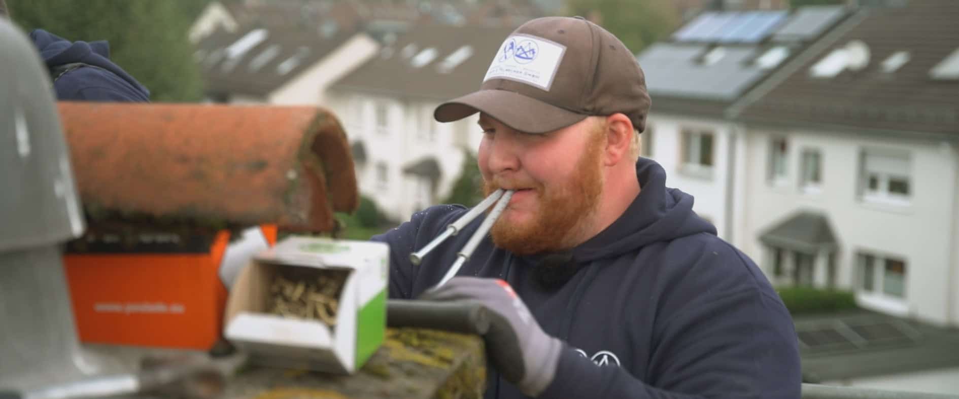 Handwerker in Arbeitskleidung arbeitet auf einem Dach