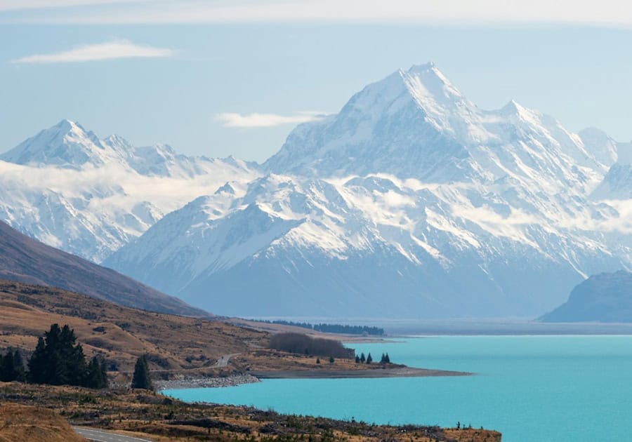 Blick auf die Bergkette des Mt Cook mit türkisfarbenem See und Straße im Vordergrund, Südinsel Neuseeland